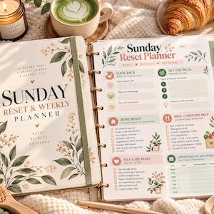 Może przedstawiać: Planer Sunday Reset & Weekly Planner z kremową okładką, botanicznymi ilustracjami i zielonym elastycznym zamknięciem. Otwarte wnętrze zawiera sekcje na zadania Look Back, Set The Week, Home Reset, Meal & Grocery Prep oraz Self-Care Reset.