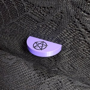 May include: A purple half-circle shaped object with a black pentagram design.