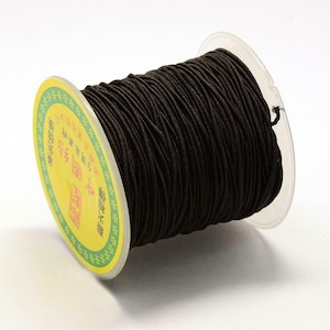 May include: A spool of black elastic cord, wound around a yellow and green label with Chinese characters. The label reads "Elastic Cord".