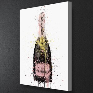 May include: A pink champagne bottle with gold and black splatters of paint on a white background.
