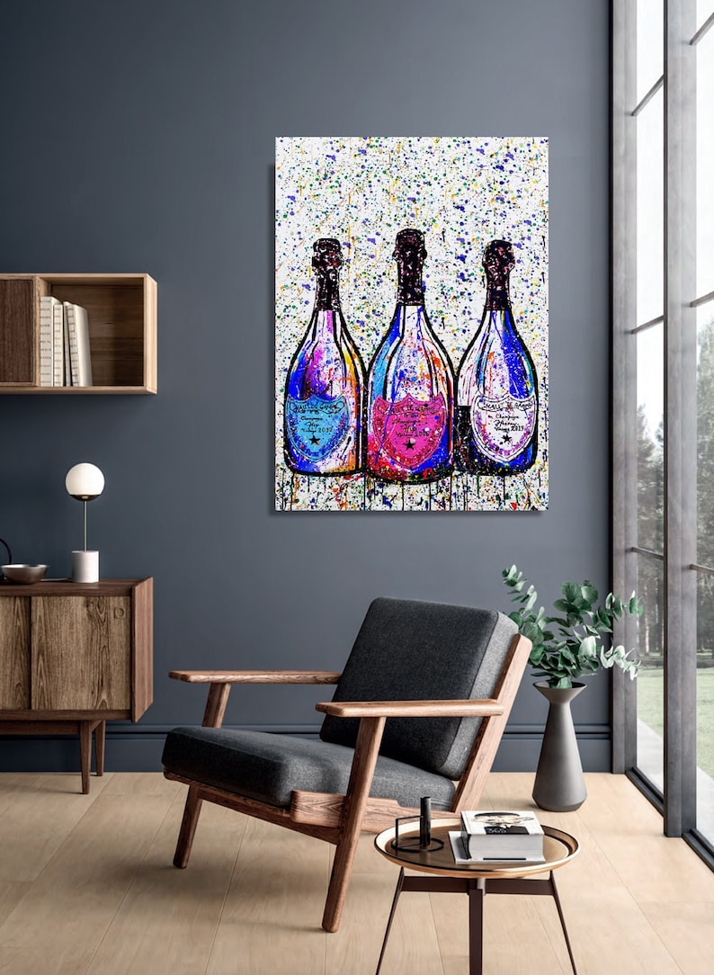 May include: Three champagne bottles with colorful paint splatters on a white background. The bottles are arranged in a row and have blue, pink, and yellow accents.