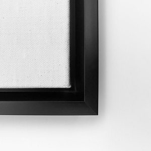 May include: Close-up of the corner of a black framed canvas print. The canvas is white and textured.