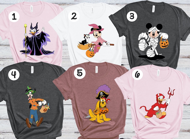 Op de afbeelding: Zes verschillende T-shirts met verschillende Disney-figuren in Halloween-kostuums. De shirts zijn roze, wit, grijs, bordeauxrood en lichtroze. De personages zijn Maleficent, Mickey Mouse, Minnie Mouse, Goofy, Pluto en Donald Duck.