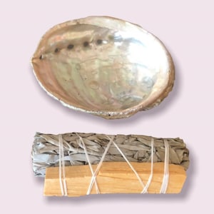 Peut inclure: Un coquillage d'ormeau blanc avec un bâtonnet de sauge enveloppé de ficelle et un bâtonnet de bois. Le bâtonnet de sauge est attaché avec de la ficelle.