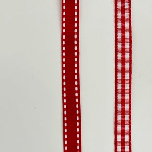 May include: Two red ribbons with white stitching. One ribbon has a solid red center with white stitching on the edges. The other ribbon has a white and red checkered pattern.