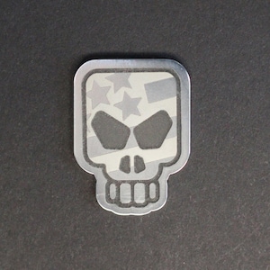 May include: A silver skull sticker with a white and gray American flag design.
