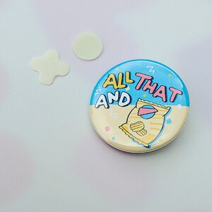 May include: A blue and yellow button with the text "All That And" and a cartoon bag of chips.