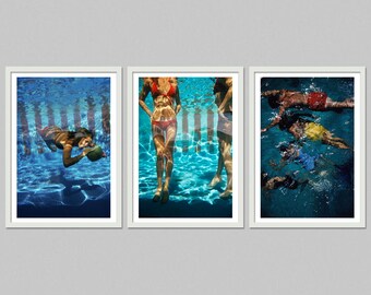 May include: Triptych of framed art prints featuring people in a swimming pool. One print shows a person underwater holding a watermelon. The other prints show people standing in the pool. The water is a vibrant blue.