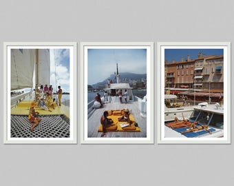 May include: Set of three framed prints featuring vintage yacht scenes. The first shows people on a yellow deck with a sail. The second depicts people sunbathing on a yacht. The third shows people sunbathing on a yacht near a city.