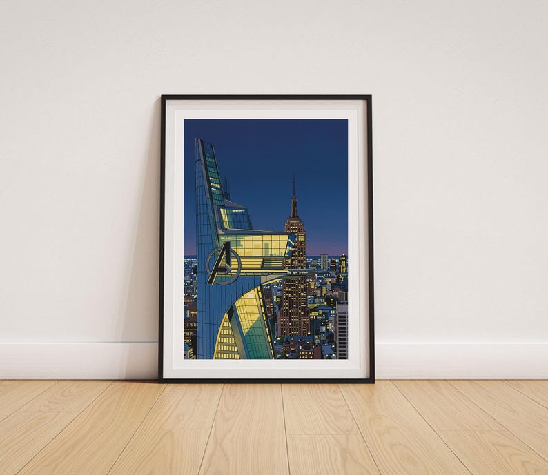Op de afbeelding: Ingelijste kunstafdruk met een gestileerde stadsgezicht bij zonsondergang. De afbeelding toont een moderne wolkenkrabber met het Avengers-logo, het Empire State Building en een levendige skyline onder een diepblauwe hemel. Het kunstwerk zit in een zwarte lijst.