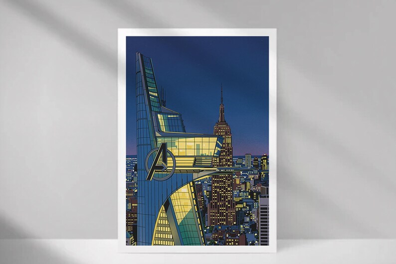 Op de afbeelding: Een ingelijste kunstdruk met een gestileerd stadslandschap 's nachts. De afbeelding toont een moderne wolkenkrabber met het Avengers-logo, naast het Empire State Building. Het kleurenpalet omvat blauw, geel en donkere tinten.