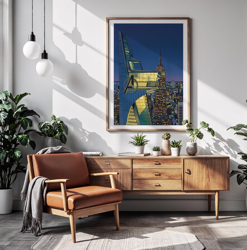 Op de afbeelding: Een ingelijste kunstdruk met een stadsgezicht met het Avengers-logo. Het kunstwerk wordt tentoongesteld boven een houten kast met een leren fauteuil en planten. De print heeft een houten lijst en toont een nachtsc&egrave;ne met verlichte gebouwen.