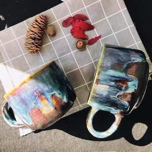 May include: Two ceramic mugs with a blue, green and brown glaze. The mugs have a unique, textured finish and are perfect for enjoying a warm beverage.