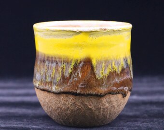 May include: A yellow and brown ceramic mug with a textured surface.