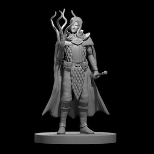 Op de afbeelding: Een grijs geverfd miniatuurbeeldje van een persoon die een lange robe draagt en een tentakelvormige staf vasthoudt. Het beeldje staat op een ronde basis.