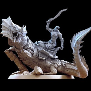 Puede incluir: Una miniatura gris y detallada de una figura humanoide montando una criatura reptiliana con una espada levantada en el aire. La criatura tiene una cola larga y una espalda espinosa. La miniatura está colocada sobre una base gris.