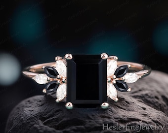 Könnte beinhalten: Ein Verlobungsring aus Roségold mit einem schwarzen Smaragdschliff-Edelstein, umgeben von kleineren weißen und schwarzen Diamanten.