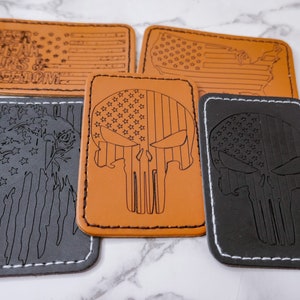 May include: Five leather patches with American flag designs. Two patches feature a skull with the American flag design. One patch features an eagle with the American flag design. One patch features the American flag with the words "Beer, Steak, Guns & Freedom". One patch features the American flag with the outline of the United States.