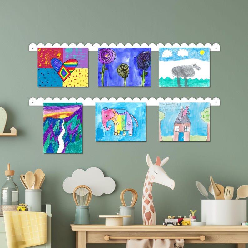 White scalloped metal wall mounted kids art display board with two rails showcasing six colorful drawings using magnets. Handmade in the USA, this kids magnet board is a beautiful and functional kids art display and kids drawing display. Ideal for playroom decor, classroom walls, or kids room decor. This artwork display sign is perfect for organizing creative masterpieces and makes a charming playroom decor sign or look what we made art display for families.