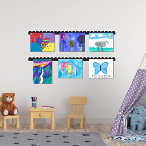 Scalloped metal kids art display board mounted on wall, featuring two rails with six colorful children’s drawings held by pushpin magnets. Handmade in the USA, this kids artwork display is ideal for playroom wall art, kids room decor, or homeschool spaces. Perfect as a kids magnet board, kids drawing display, or artwork display sign. A fun and functional playroom decor sign that turns creativity into cherished decor. Great gift for parents or grandparents to showcase art.