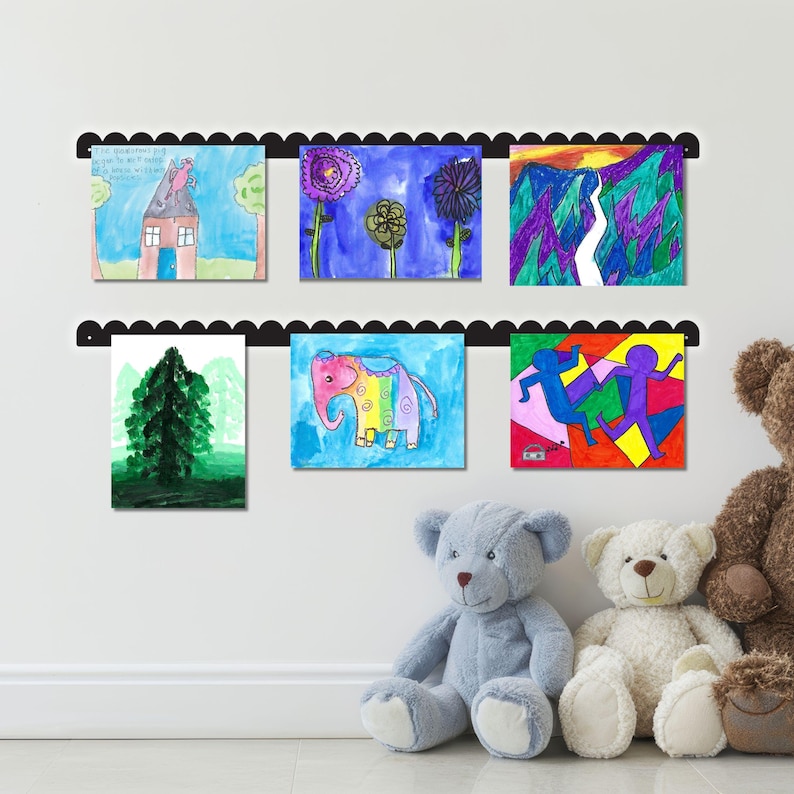 Wall mounted scalloped metal kids art display board with two rails holding six colorful kids drawings using pushpin-style magnets. Handmade in the USA, this kids artwork display is perfect for showcasing creativity in a nursery, homeschool, or play space. Ideal as a kids magnet board, kids drawing display, or playroom decor sign. A functional and charming artwork display sign for playroom wall art or kids room decor that celebrates children’s imagination and expression.
