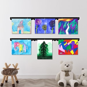 Handmade metal kids artwork display board with scalloped edges, wall mounted and holding six colorful children’s drawings with pushpin magnets. This kids magnet board is perfect for showcasing creativity in a cozy playroom or nursery. Works beautifully as a kids drawing display, art display board, or playroom decor sign. Ideal for kids room decor, classroom use, or as a look what we made artwork display sign proudly made in the USA.