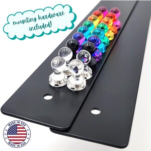Close-up of black metal kids magnet board with colorful pushpin-style magnets and pre-drilled holes, showcasing included mounting hardware. Handmade in the USA, this durable art display board is perfect as a kids art display, kids drawing display, or artwork display sign. Ideal for playroom decor, classroom walls, or kids room decor. A functional and stylish way to showcase creativity with this magnetic playroom decor sign.
