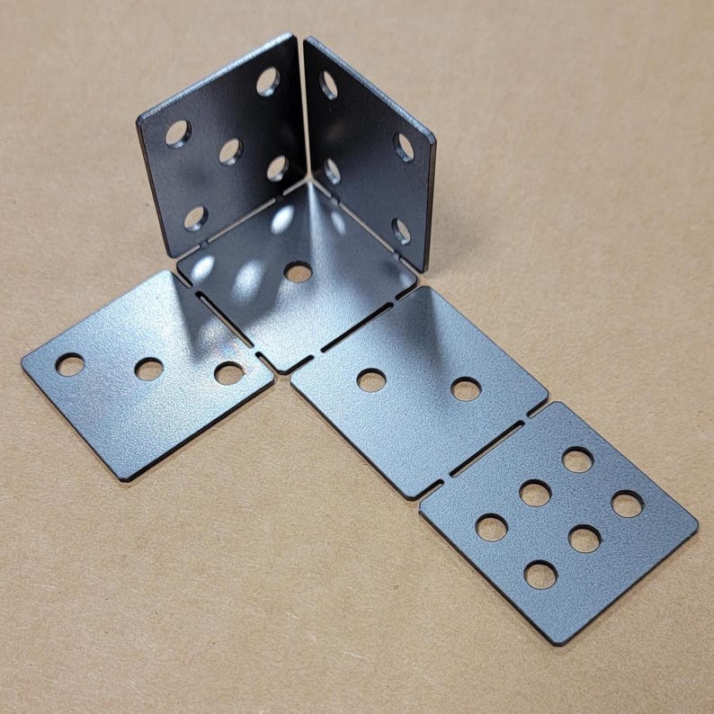 May include: A set of five metal corner brackets with multiple holes for attaching to wood or other materials. The brackets are silver in color and have a slightly textured finish.