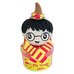 May include: A red and yellow slime container with a Harry Potter character on top. The container has the text "The Chosen Slime" on the front.