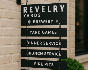 Peut inclure: Panneau métallique noir accroché à un mur de briques. Il affiche "REVELRY YARDS BREWERY" et énumère "YARD GAMES", "DINNER SERVICE", "BRUNCH SERVICE", "FIRE PITS" et "WOOD FIRED PIZZA" en texte blanc.