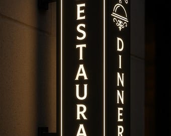 Könnte beinhalten: Schwarzes rechteckiges Restaurantschild mit dem Wort „RESTAURANT“ vertikal in Weiß, umrandet von einem weißen Rahmen. Die Seite des Schildes zeigt „DINNER“ in Weiß. Das Schild ist an einer Wand befestigt.