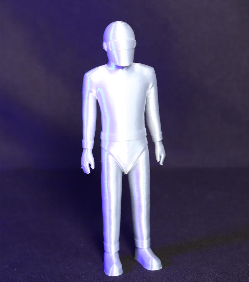 May include: A white plastic action figure of a robot wearing a helmet with a visor. The figure is standing with its arms at its sides.