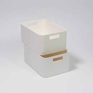 May include: Two stacked, off-white storage containers. Each container has a rectangular shape with rounded corners and a ribbed texture. They feature rectangular cut-out handles on the sides. Ideal for home organisation.