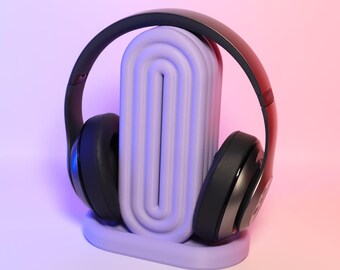 May include: Black over-ear headphones with a purple stand. The stand has a unique design with multiple ridges.