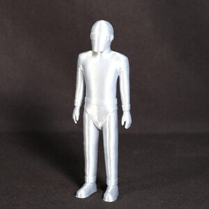 May include: A silver-colored 3D printed figurine of a person wearing a helmet and a one-piece suit.