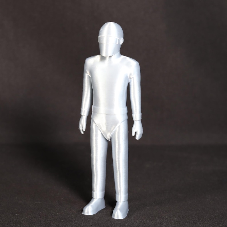 May include: A silver-colored 3D printed figurine of a person wearing a helmet and a one-piece suit.