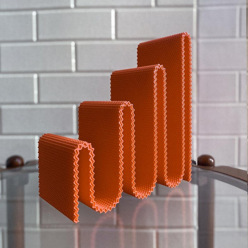 May include: Four orange, textured, rectangular objects arranged in a stepped pattern. Each object has a zig-zag edge. The objects are set against a white tiled background.
