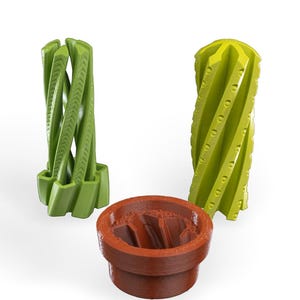 May include: Three 3D printed objects: two green spiral-shaped pieces and a brown cylindrical piece with a spiral-shaped opening.