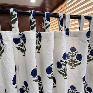 May include: White curtains with a repeating pattern of blue floral designs and green leaves. The curtains are hanging from a black rod with matching blue and green patterned tabs.