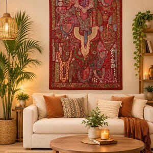 Puede incluir: Un tapiz rectangular que presenta un mosaico de paneles de tela roja adornados con intrincados bordados, hilos metálicos, lentejuelas y abalorios. La pieza textil está rematada con un borde rojo y pequeñas borlas en las esquinas superiores.