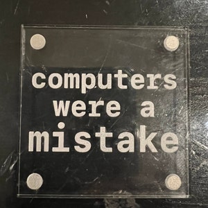 May include: A clear acrylic sign with rounded corners and silver accents. The sign reads "computers were a mistake".