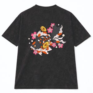 May include: Dark gray t-shirt featuring a detailed illustration of a koi fish with black, orange, and white scales, accented by pink cherry blossoms and gold coins. The design is on the back of the shirt, creating a unique and artistic look.