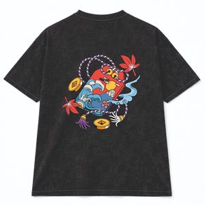 May include: Dark gray t-shirt with a colorful graphic on the back. The graphic features a red rectangle with a cartoon face, waves, coins, and maple leaves. The shirt has short sleeves and a crew neck.