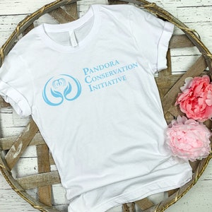 May include: White t-shirt with a blue logo that says "Pandora Conservation Initiative" and a stylized blue flower graphic.