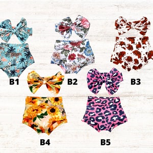 Puede incluir: Cinco conjuntos de cubrepa&ntilde;ales para beb&eacute; con lazos a juego, etiquetados de B1 a B5. B1 presenta un estampado tropical en azul verdoso con flamencos. B2 tiene un patr&oacute;n floral. B3 muestra un estampado de vaca marr&oacute;n y blanco. B4 muestra girasoles amarillos. B5 tiene un estampado de leopardo rosa.