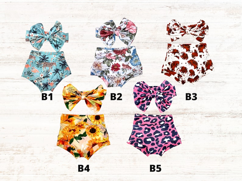Puede incluir: Cinco conjuntos de cubrepa&ntilde;ales para beb&eacute; con lazos a juego, etiquetados de B1 a B5. B1 presenta un estampado tropical en azul verdoso con flamencos. B2 tiene un patr&oacute;n floral. B3 muestra un estampado de vaca marr&oacute;n y blanco. B4 muestra girasoles amarillos. B5 tiene un estampado de leopardo rosa.
