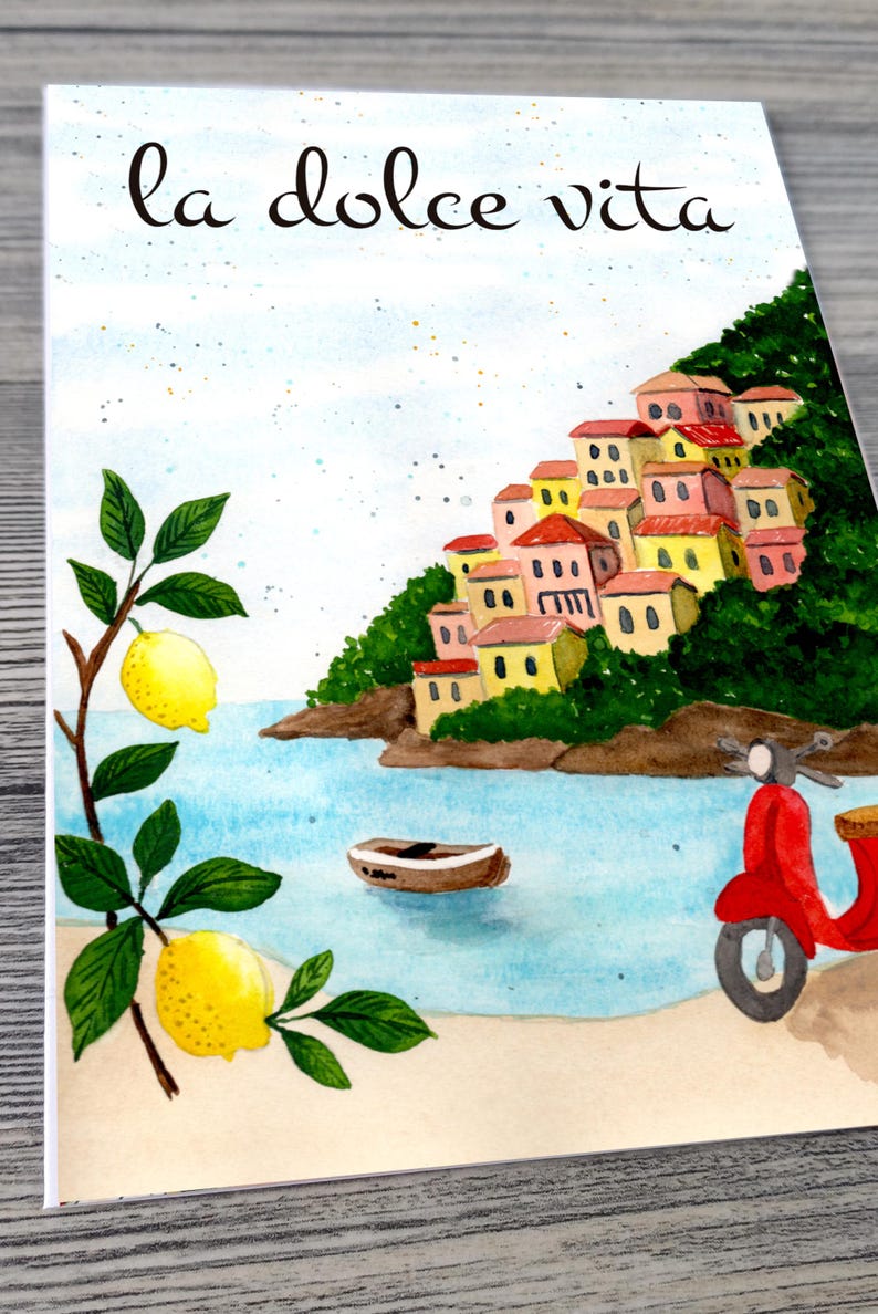 May include: Watercolor illustration featuring the phrase "la dolce vita" above a coastal scene. The image depicts colorful buildings on a hillside, a red scooter, a small boat, and lemon branches.