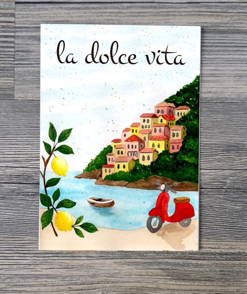 May include: Watercolor illustration of a coastal Italian scene with the text "la dolce vita." The image features a red scooter, buildings on a hillside, a boat, lemons, and the sea.