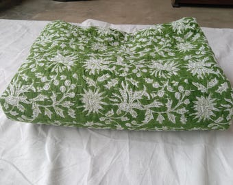 May include: A folded green quilt featuring a white floral pattern with detailed botanical illustrations of flowers and leaves. The fabric has a visible quilted texture with fine stitching lines running across the surface of the textile.