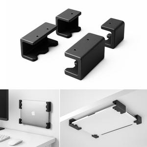May include: Four black metal brackets with a C-shaped design, ideal for mounting. The brackets are shown in a group and also in use, holding a laptop and a shelf. The brackets have a matte finish and a minimalist aesthetic.